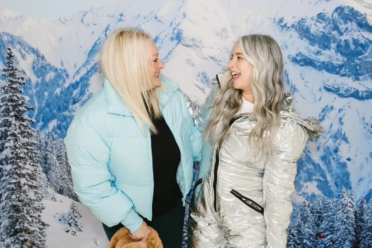 Two guests laughing at a snowy mountain photo booth backdrop. A photo booth setup we bring to Reno events
