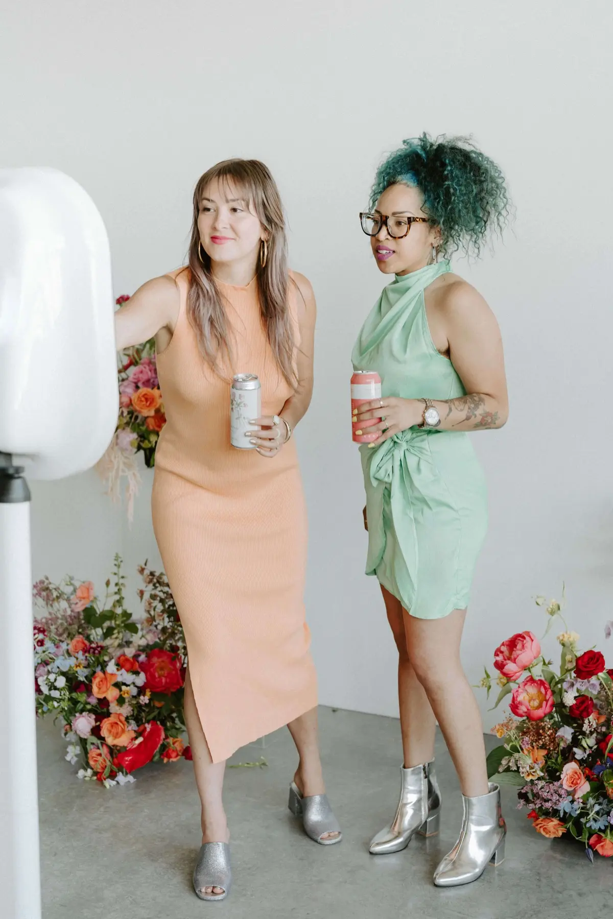 Two guests in pastel dresses at a photo booth with a floral backdrop. A photo booth setup we bring to San Diego events