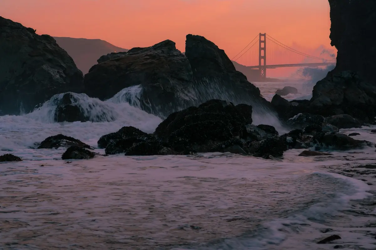 The Golden Gate Bridge at sunset seen from the rocky shore