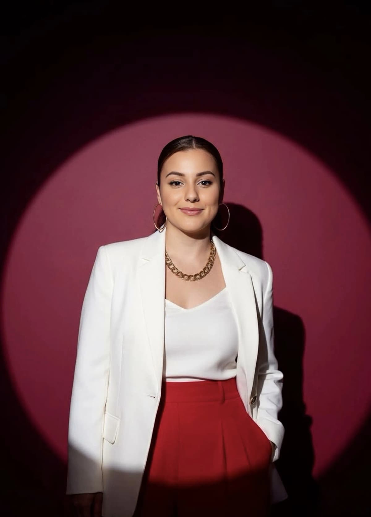 Liz Colón, founder of Captured Celebrations, in a white blazer against a berry backdrop