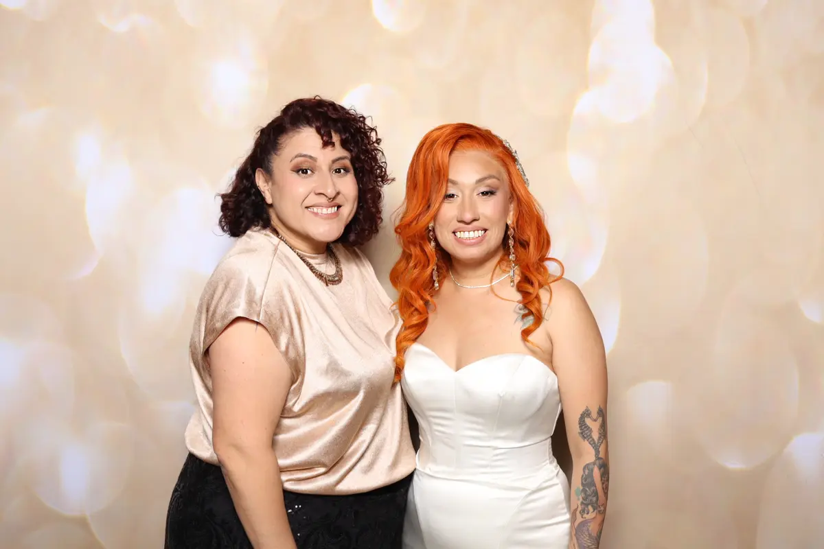 The bride and a guest smile together at the wedding photo booth at Hart & Main