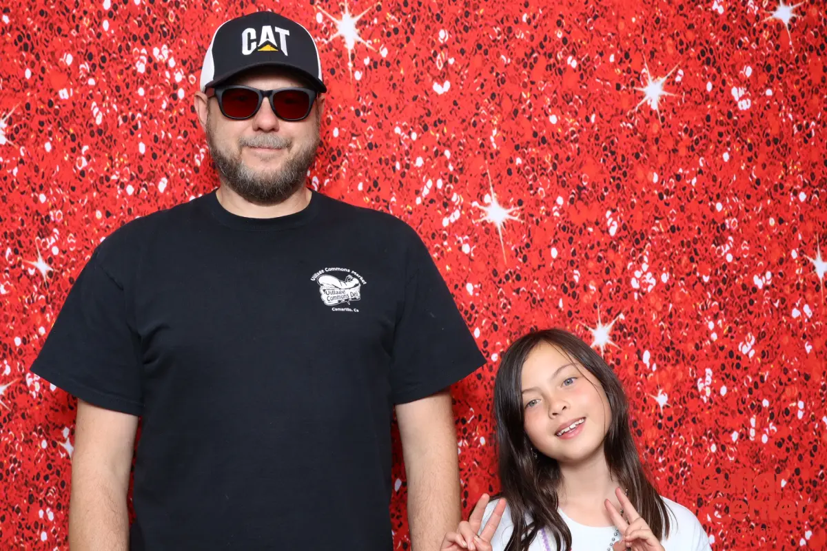Guests posing together at the Red Ruby Sparkle backdrop during the Guitar Center Service Awards Jam Night photo booth activation in Thousand Oaks CA
