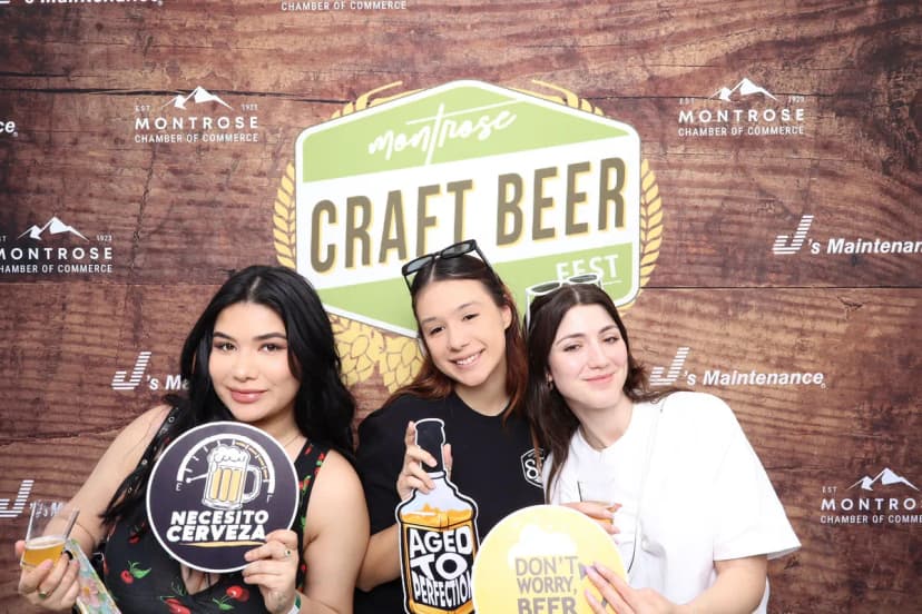 Friends posing at the Captured Celebrations step-and-repeat photo booth at Montrose Craft Beer Fest 2026