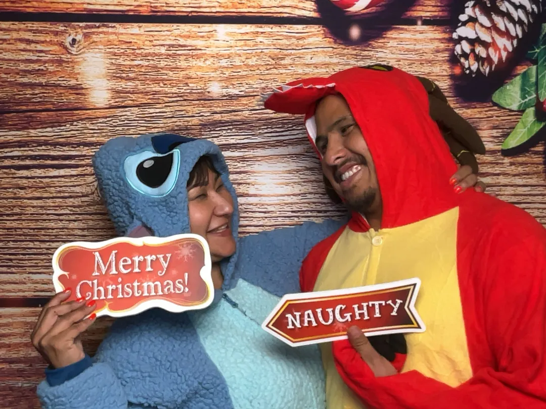 Couple in Christmas costumes holding Merry Christmas and Naughty signs