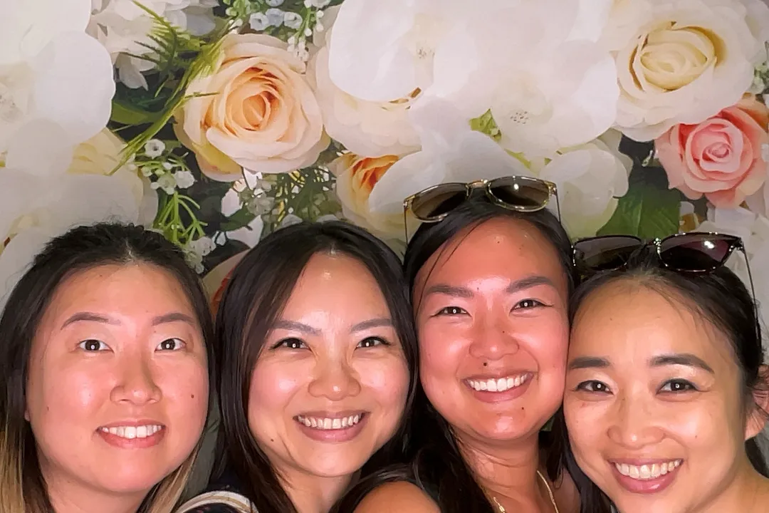 Four friends smiling at camera in photo booth