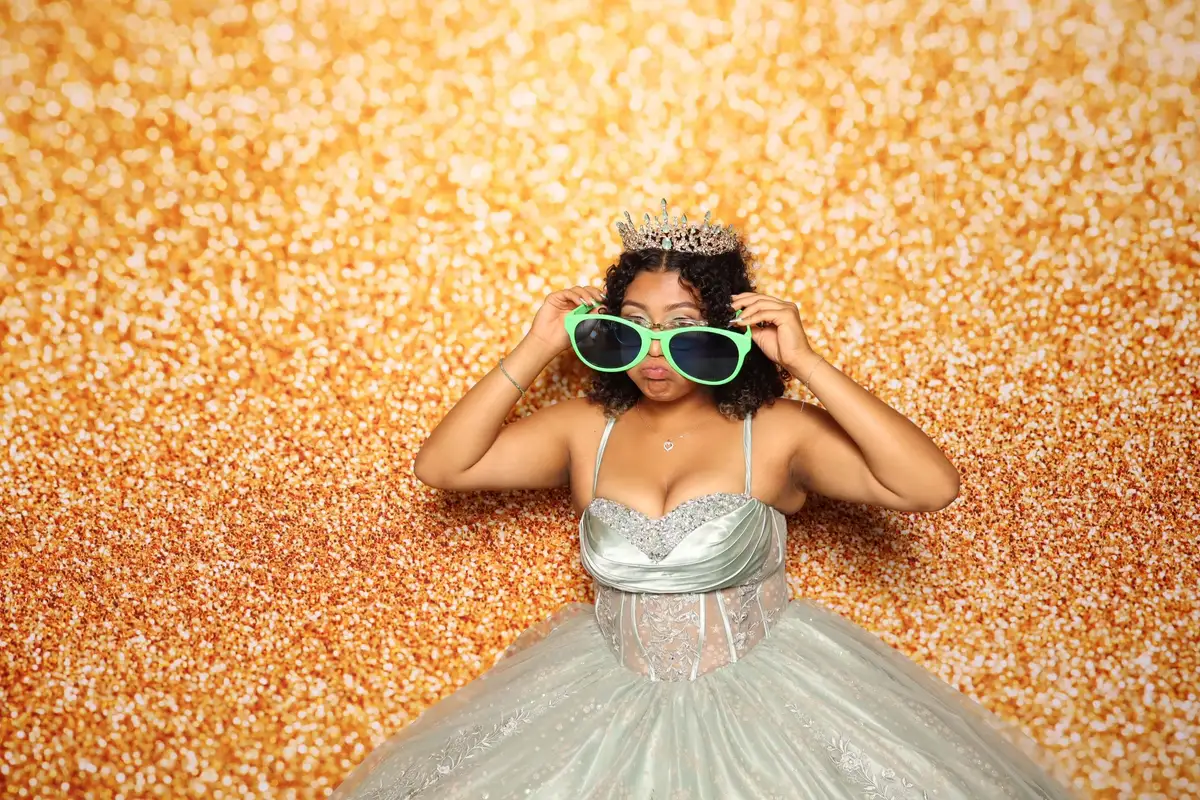 Quince posing in front of the gold backdrop 