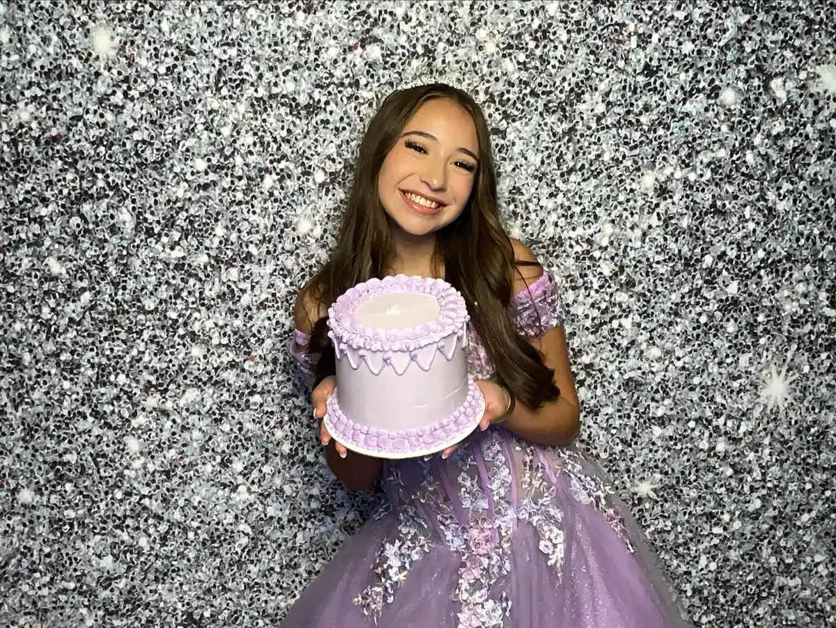 Quince posing in front of a silver sequin backdrop 
