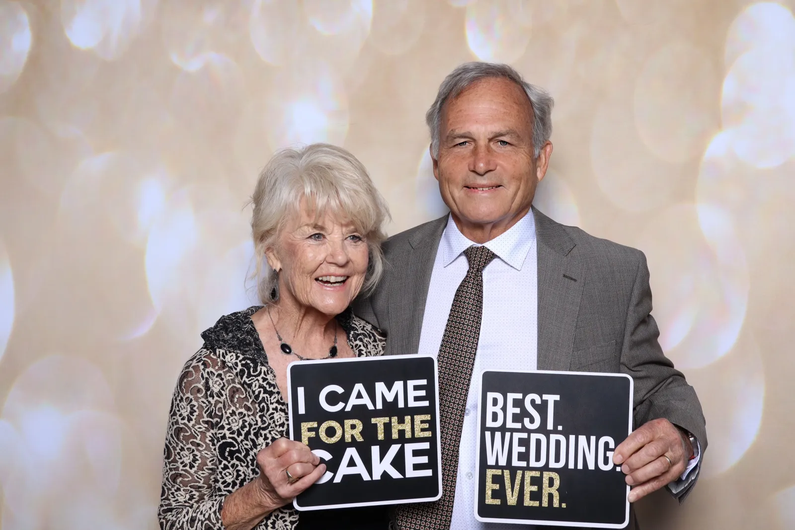 Two wedding guests holding Best Wedding Ever and I Came for the Cake signs at the Captured Celebrations photo booth at Gerry Ranch in Camarillo